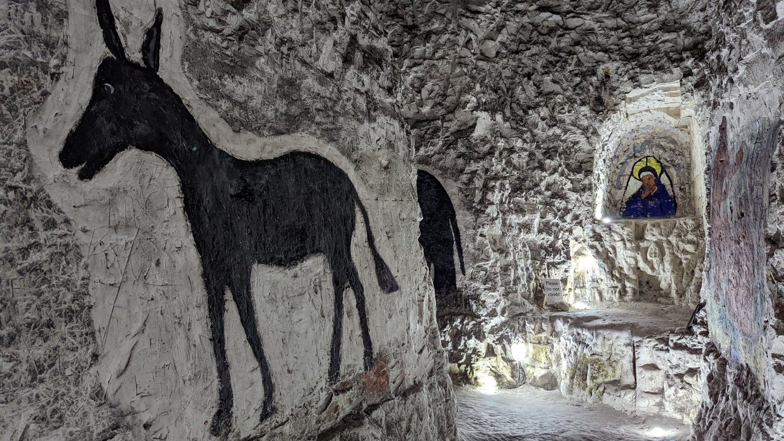 The long main tunnel with side cut away tunnels and figures drawn on the chalk walls.
